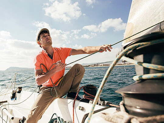 Male sailor working the rigging on the sales to improve course.